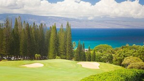 A golf course with a view of the ocean and mountains.
