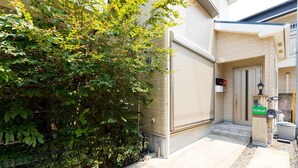 Un immeuble résidentiel avec un portail de garage fermé, un petit porche avec des marches et une boîte aux lettres.