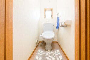 A compact bathroom with a toilet, towel rack, and patterned rug.