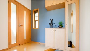Un couloir avec un plancher en bois, un mur bleu, une armoire avec un miroir et une petite fenêtre.