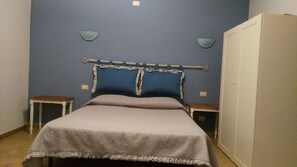 Une chambre à coucher comprenant un lit, une armoire, deux tables de chevet et des appliques murales.