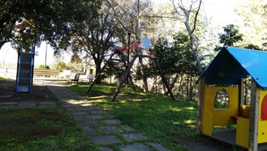 Une aire de jeux avec un toboggan, des balançoires et une petite maison de jeu.