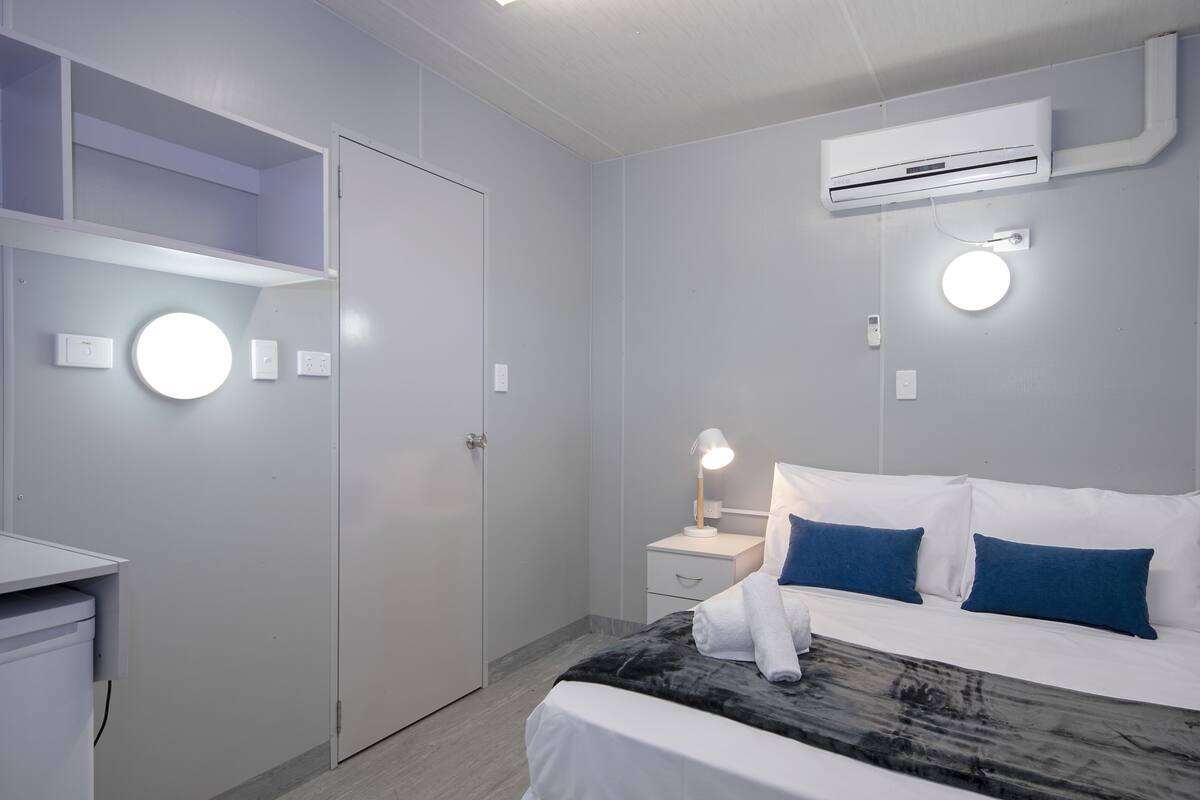 Une chambre d’hôtel moderne, équipée d’un lit, d’une table de chevet et d’une armoire.