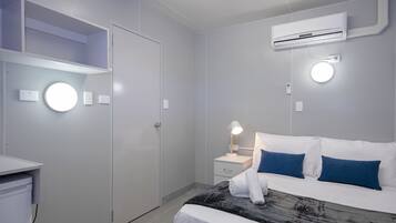 Ein modernes Hotelzimmer mit Bett, Nachttisch und Kleiderschrank.