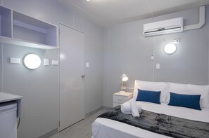 A modern hotel room with a bed, bedside table, and a wardrobe.