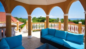 A covered outdoor seating area with a view of the ocean.