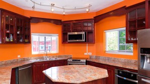 A kitchen with wooden cabinets, a central island, stainless steel appliances, and a window with blinds.