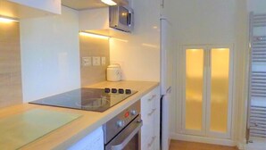 Une cuisine de taille réduite équipée d’une cuisinière, d’un four, d’un four à micro-ondes et d’un réfrigérateur.
