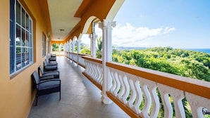 A covered balcony with a view of a lush landscape.