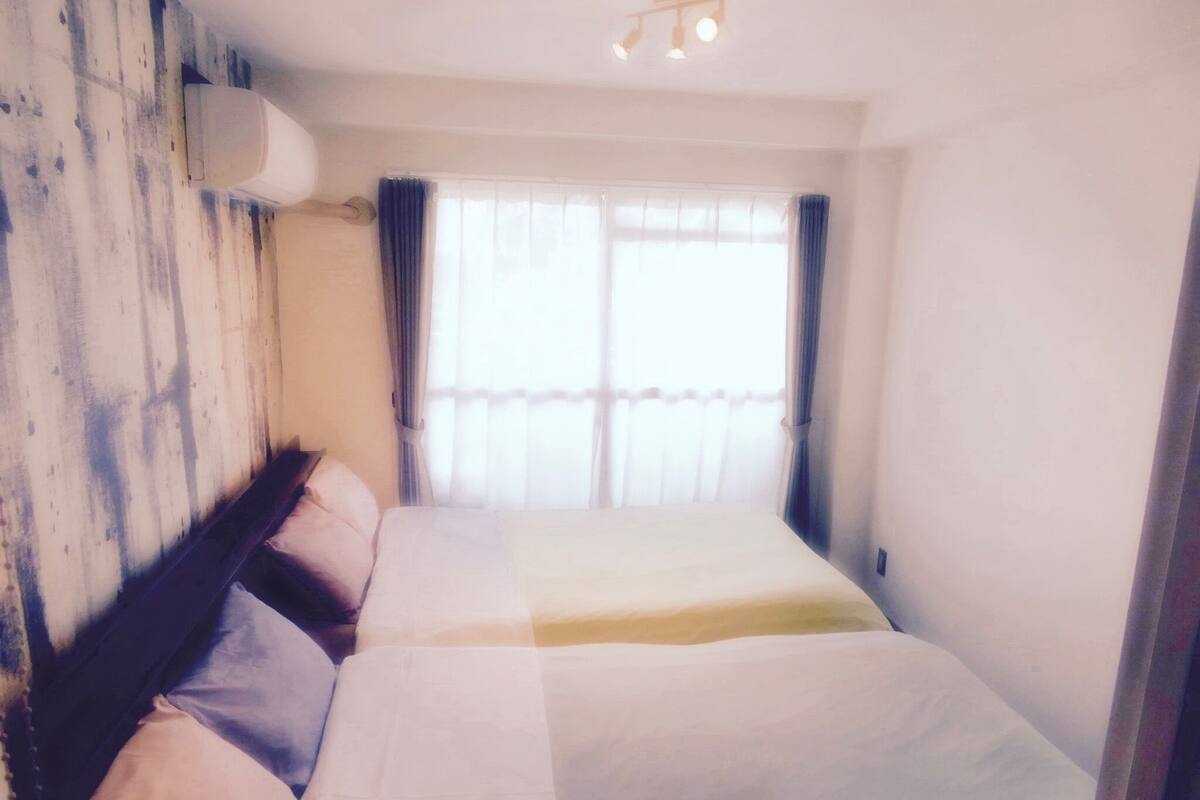 Ein Hotelzimmer mit einem großen Bett, einem Kopfteil, einem Fenster mit Vorhängen und einer Deckenleuchte.