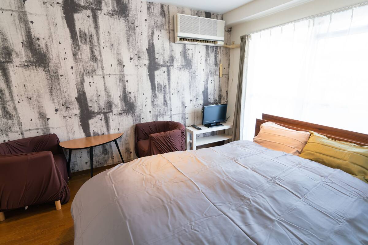 Ein Hotelzimmer mit einem großen Bett, einem Fernseher, einem kleinen Tisch und einem Sessel.