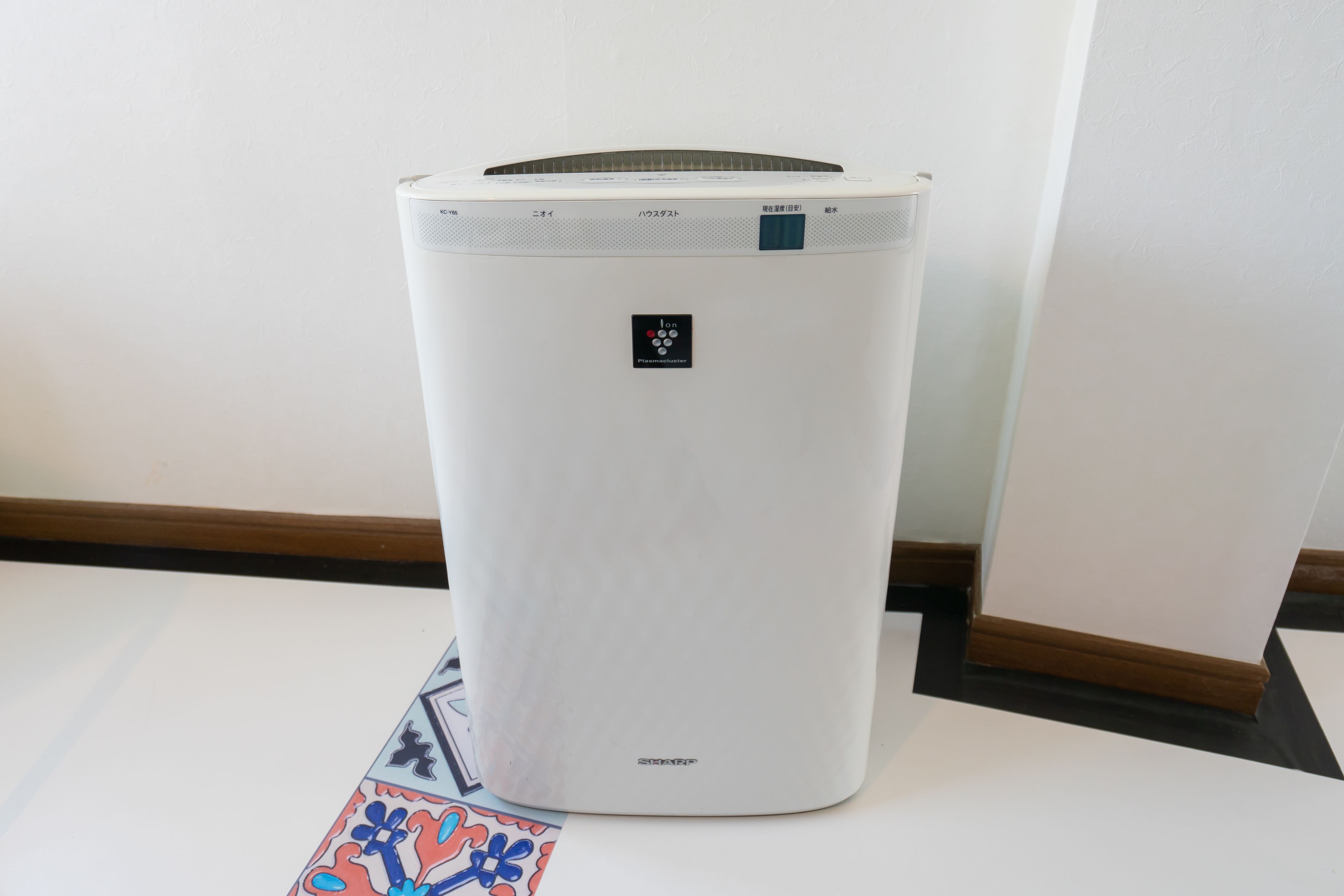 A white portable air conditioner with a control panel and a small logo on the front.