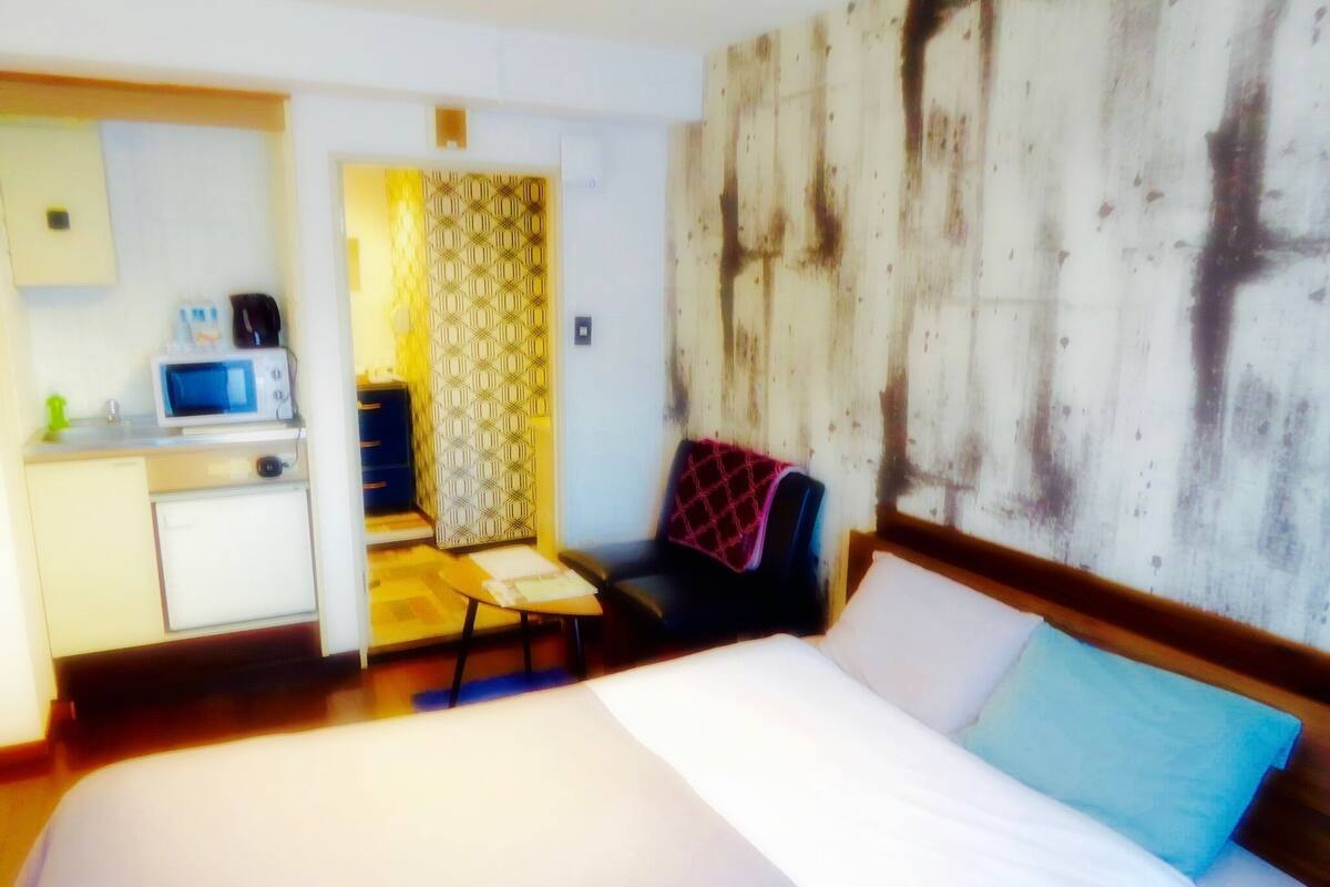 Ein Hotelzimmer mit Bett, Schreibtisch mit Mikrowelle, Stuhl und einem gemusterten Vorhang.