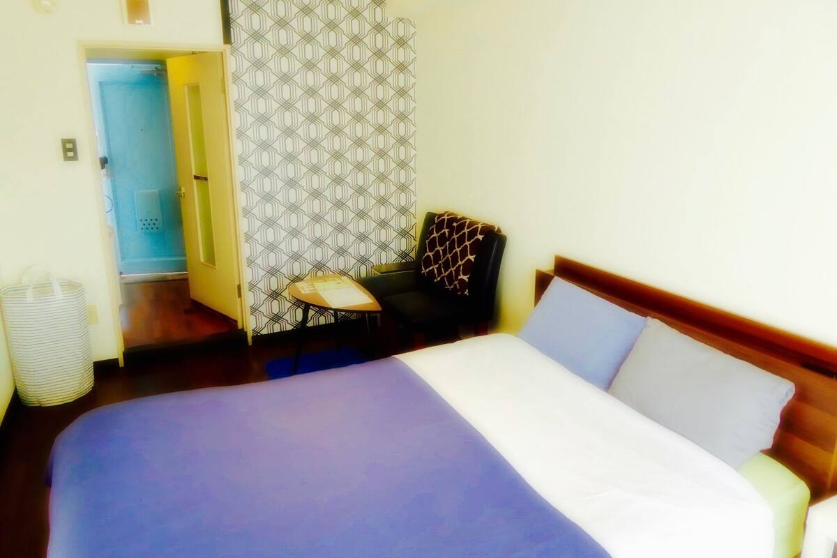 Ein Hotelzimmer mit einem großen Bett, einem Sessel, einem kleinen Tisch und einer Wand mit Muster.