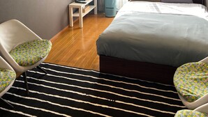 Quarto de hotel com cama, escrivaninha, cadeira, televisão e janela com cortinas.
