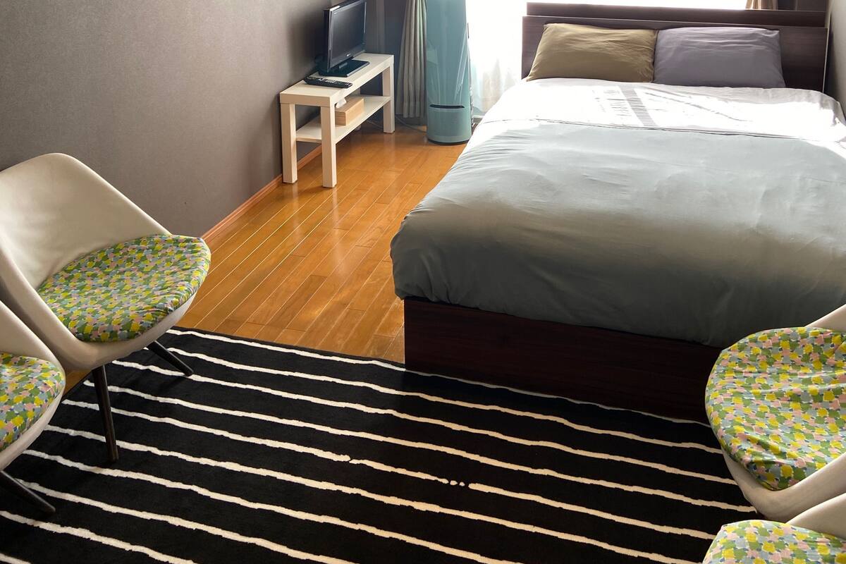Ein Hotelzimmer mit Bett, Schreibtisch, Stuhl, Fernseher und einem fenster mit Vorhängen.