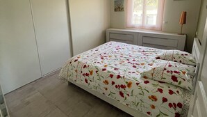 Ein Schlafzimmer mit Bett, Fenster, Heizkörper und Tür.