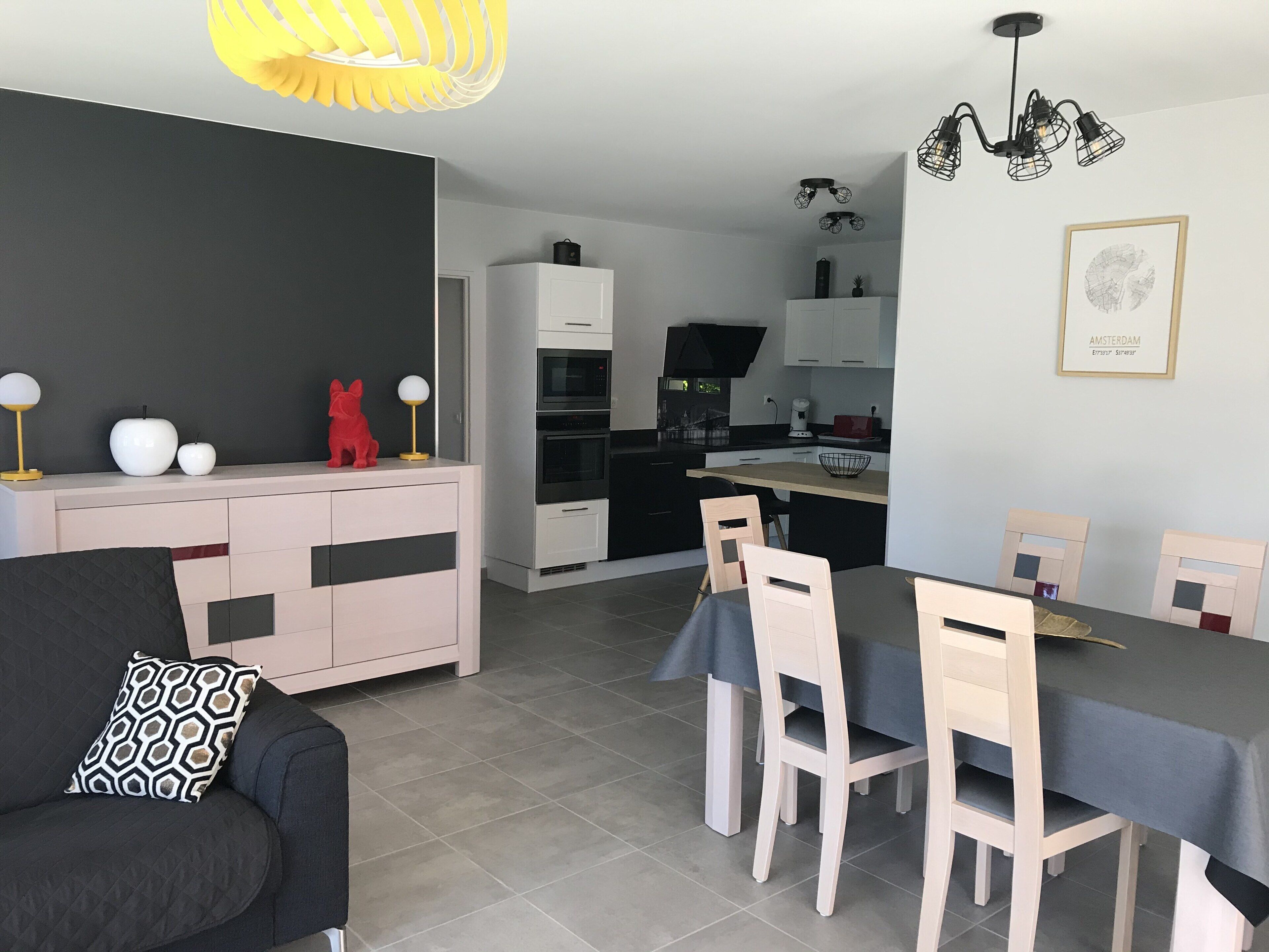 A modern kitchen with white cabinets, a black countertop, and a dining area with a table and chairs.