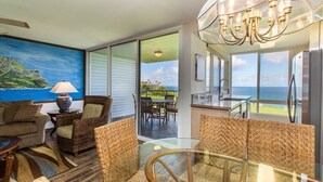 A spacious balcony with a view of the ocean, furnished with wicker chairs and a glass table. - Breathtaking Oceanfront Condo (Princeville)