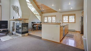 Een ruime keuken met een centraal eiland, grote ramen en een hoog plafond met houten balken.