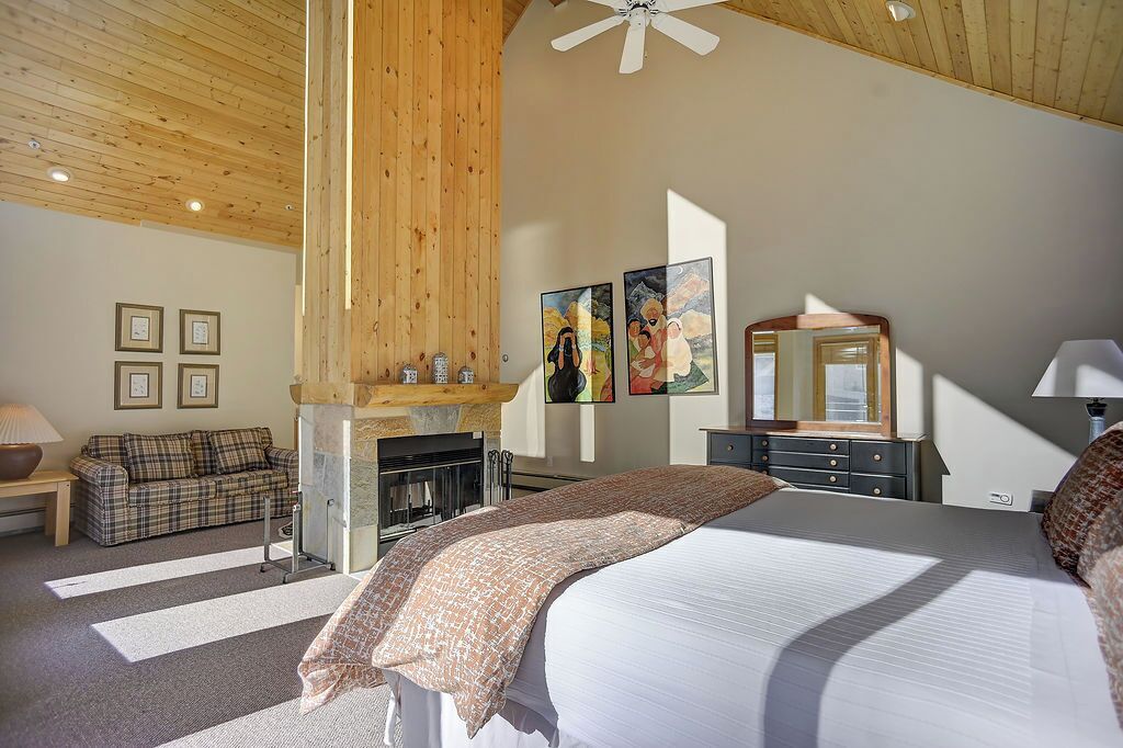 Un dormitorio con cama, chimenea, sofá y cómoda.