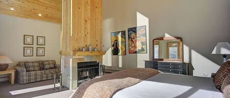 Un dormitorio con cama, chimenea, sofá y cómoda.