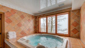 Een hottub in een hoek, met uitzicht op bomen door een raam.