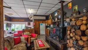 A cozy lodge interior with a living area featuring red sofas, a wooden coffee table, and a fireplace. - Kookaburra Ski Lodge (Jindabyne)