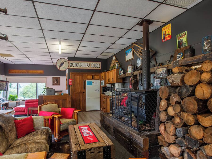 A cozy lodge interior with a living area featuring red sofas, a wooden coffee table, and a fireplace.