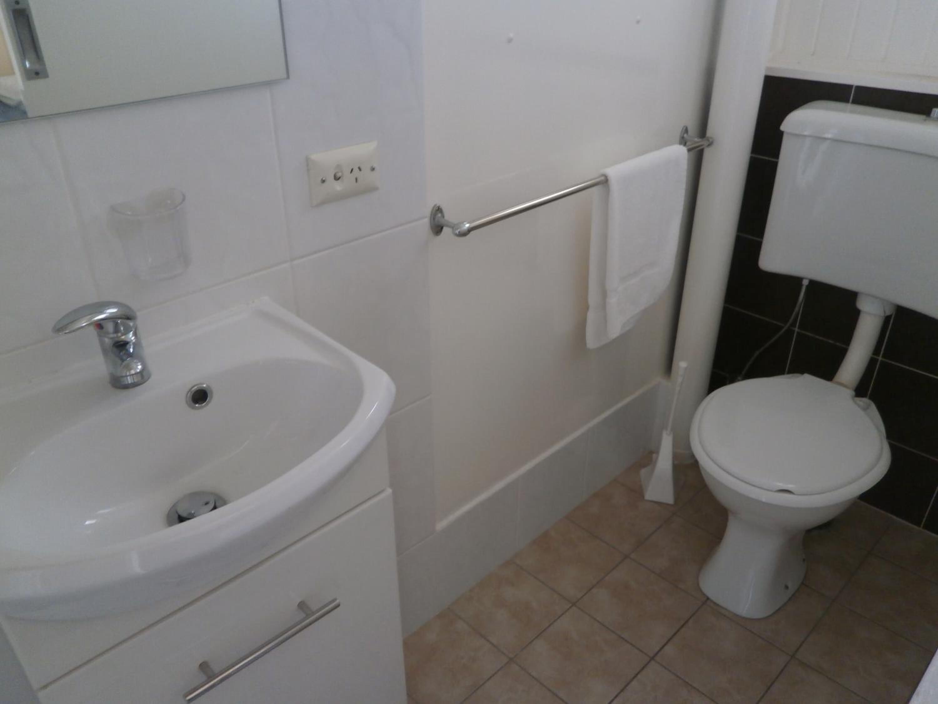 A bathroom with a white sink, a toilet, and a towel rack.