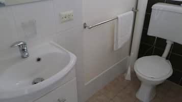 A bathroom with a white sink, a toilet, and a towel rack.