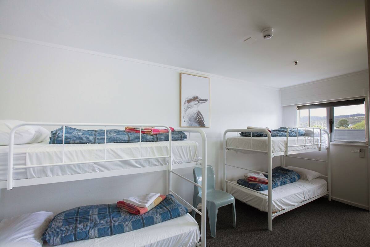 Ein Schlafsaalzimmer mit Etagenbetten, einem Fenster mit Blick und einem Deckenventilator.