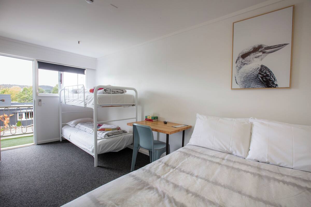 Ein Zimmer mit Etagenbetten, einem Schreibtisch, einem Stuhl und einem Bett.