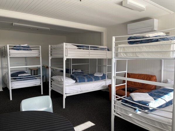 A bunk bed room with white metal frames, a small table, and a chair.
