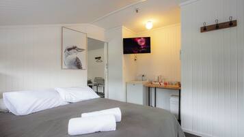 Ein Hotelzimmer mit einem Bett, einem Schreibtisch, einem Spiegel und einem an der Wand befestigten Fernseher.