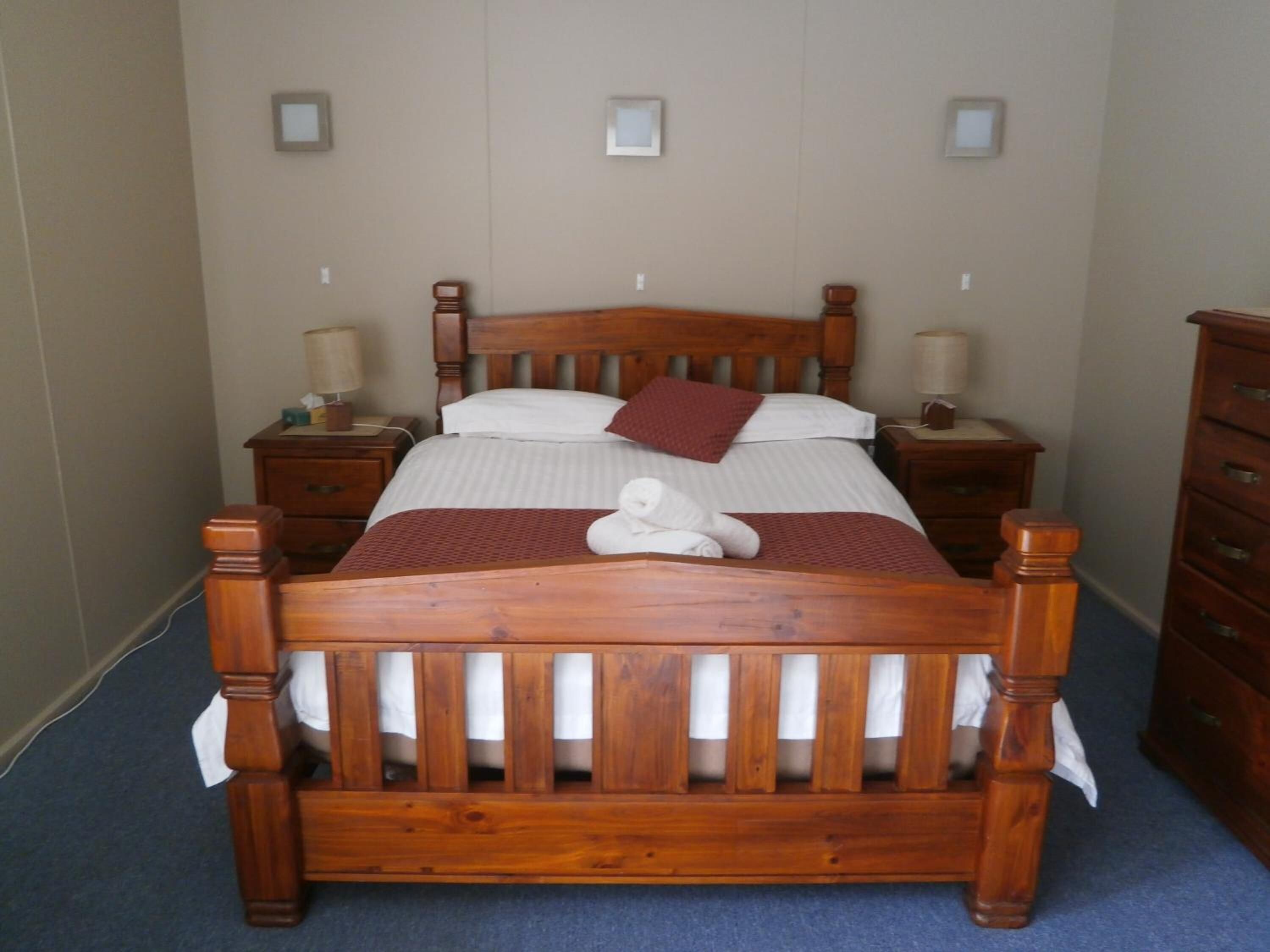 A wooden bed with a headboard, two bedside tables, and a wooden dresser.
