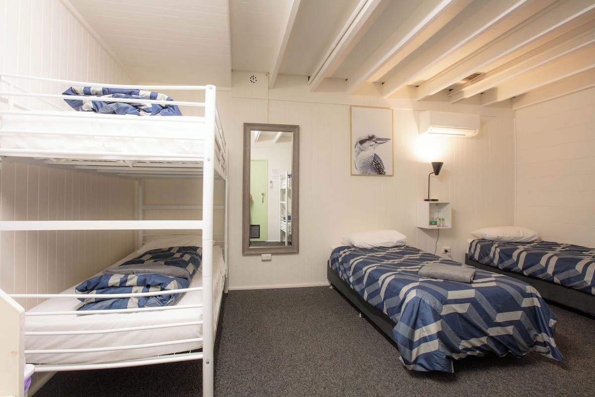 Ein Schlafsaalzimmer mit Etagenbetten, einem Spiegel, einer Wandleuchte und einem gerahmten Bild.