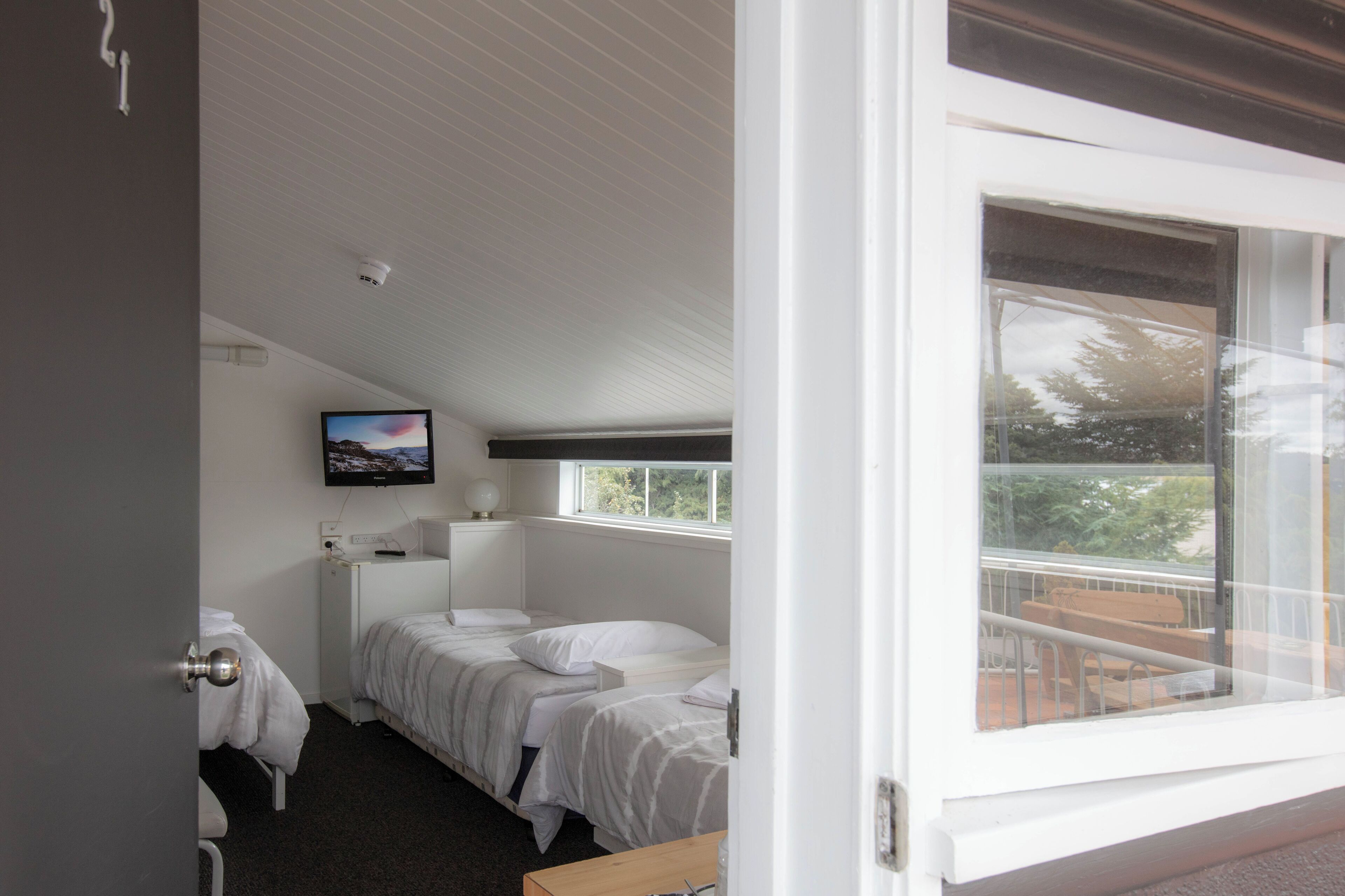 Une chambre d’hôtel avec deux lits, une télévision et une fenêtre donnant sur un balcon.