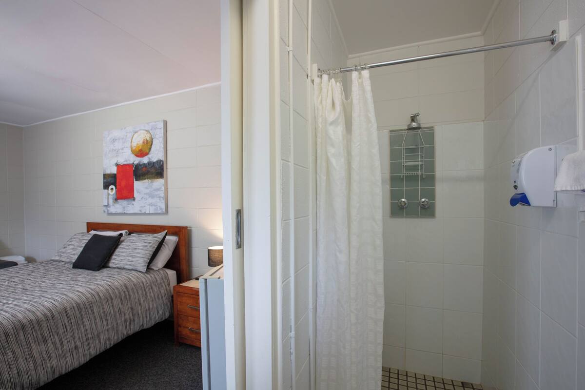 Ein Hotelzimmer mit Bett, Dusche und einem Badezimmer mit Glasabtrennung.