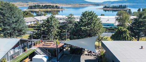 A building with a sloped roof, a covered outdoor area with a roof, and a view of a lake and mountains in the background.