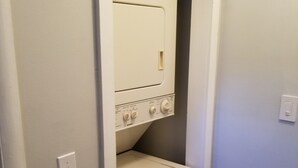 Un lavadero pequeño con lavadora y secadora, un panel de control y un interruptor de luz.