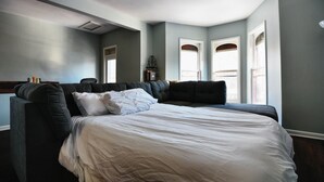 Un dormitorio con una cama grande, cabecera tapizada oscura y paredes azul claro.