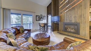A spacious living room with leather sofas, a fireplace, a TV, and a dining area.