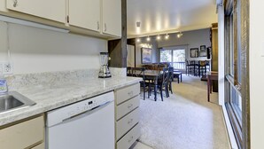A kitchen with white cabinets, a built-in dishwasher, and a blender on the counter.