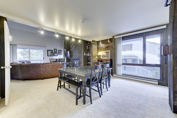 Un salon spacieux avec une grande table à manger, une cheminée et une vue sur l’extérieur.
