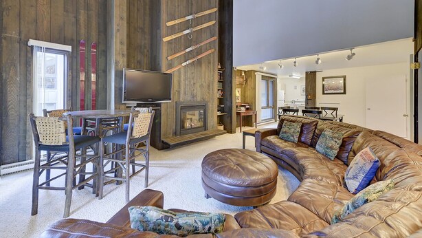 A cozy living room with a large L-shaped sofa, a fireplace, and a television.