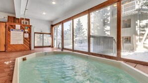A large indoor swimming pool with wooden flooring and large windows.