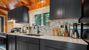 A modern kitchen with dark cabinets, a stainless steel sink, and a window above the counter.