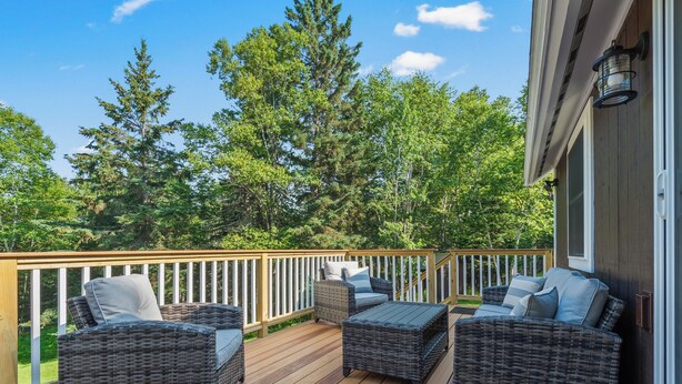 A deck with wicker furniture and a railing.