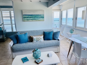 A modern living room with a sofa, a table, and a view of the sea. - Romantic Studio Apartment with Amazing View (Cabo Rojo)